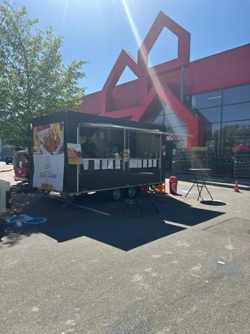 Schwarzer Catering-Anhänger vor einem Gebäude mit roter Fassade
