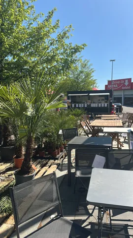 Sitzplätze und Sonnenschirme im Grünen mit Foodtruck im Hintergrund