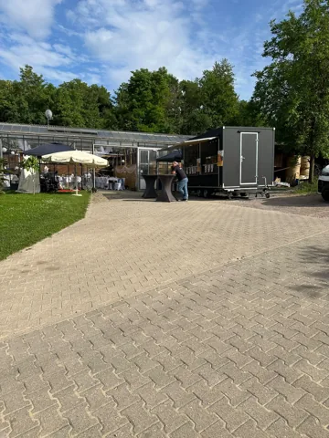Foodtruck neben einem überdachten Veranstaltungsbereich und Stehtischen