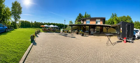 Weitläufiger Außenbereich mit Bänken, Sonnenschirmen und Foodtruck