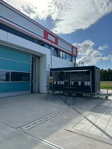 Foodtruck mit Stehtischen an einem Firmengebäude